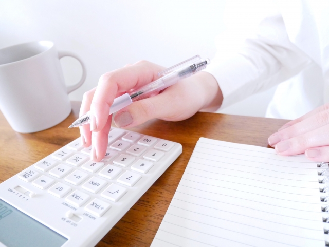 白い電卓で家計管理をする女性の写真