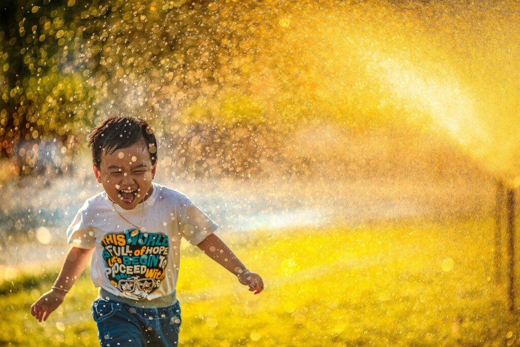 水飛沫を浴びる笑顔の子どもの画像