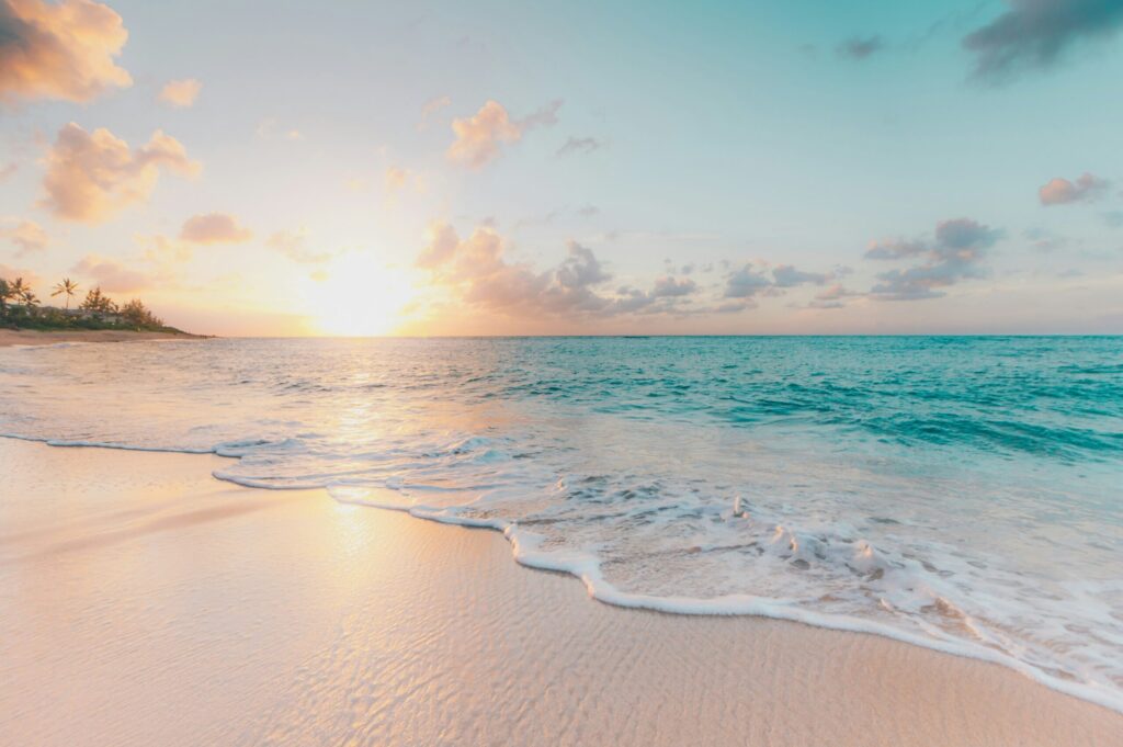 夕日が沈みつつある海辺の画像