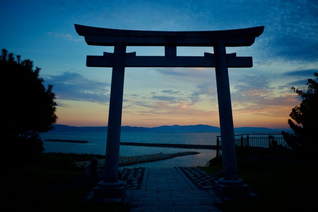 夕暮れの海辺に立つ鳥居のシルエット(イメージ画像)