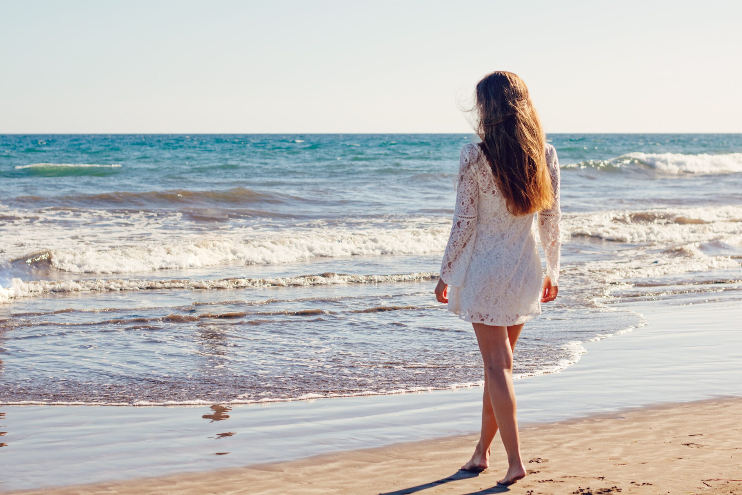 海辺で海を見つめる女性のうしろ姿（自由に羽ばたくイメージ）