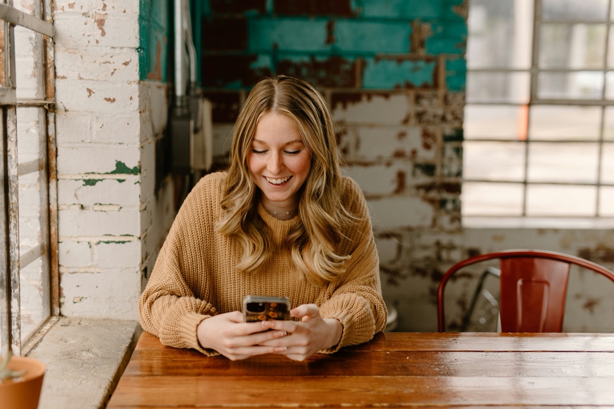 カフェでスマートフォンを見ながら微笑む女性